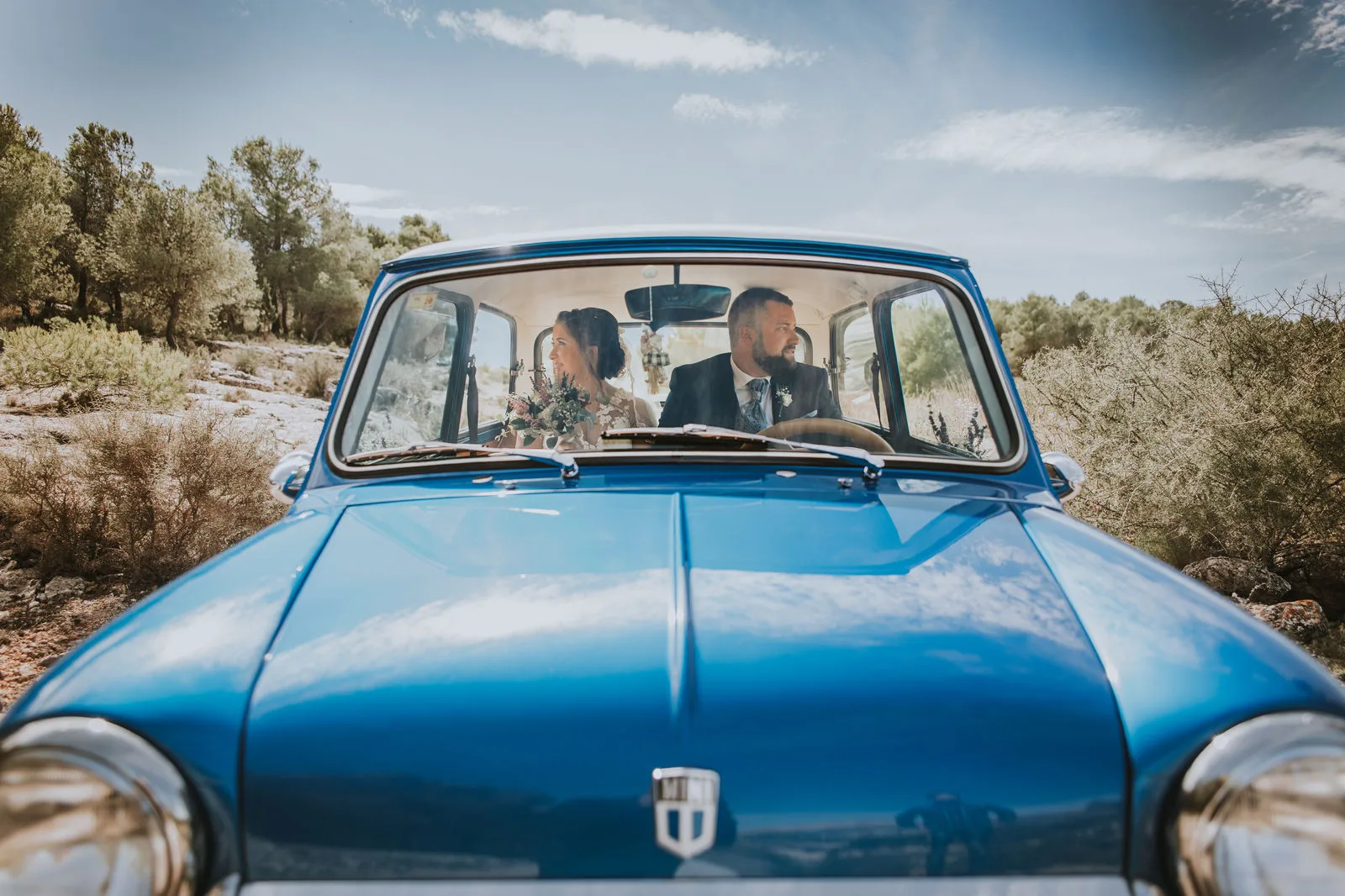 Novios llegando en un coche clásico azul