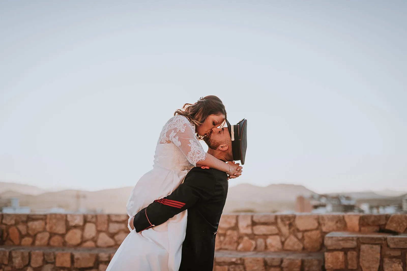 Pareja besándose frente a una puesta de sol