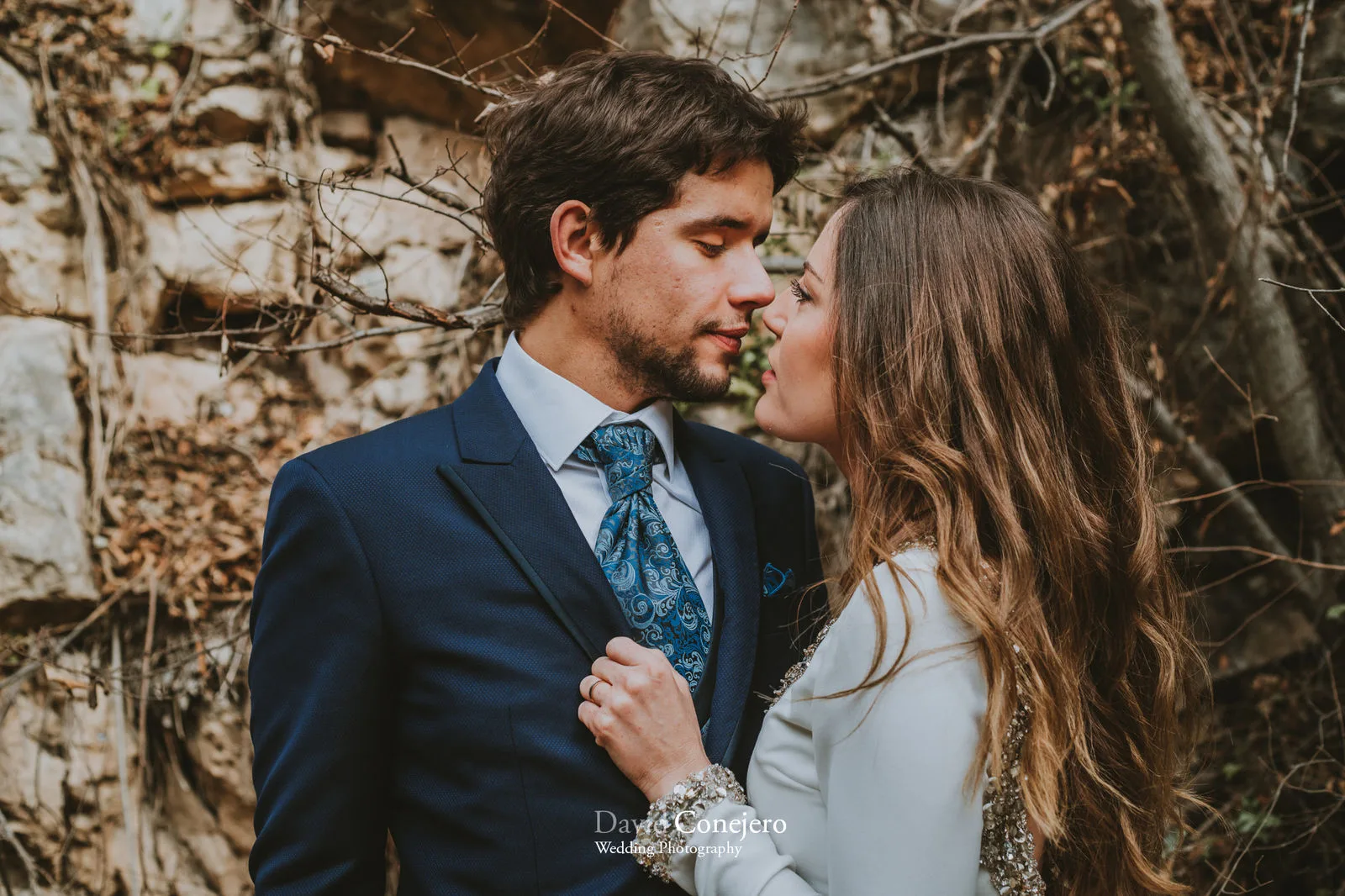 Primer plano de una pareja junto a un muro de piedra