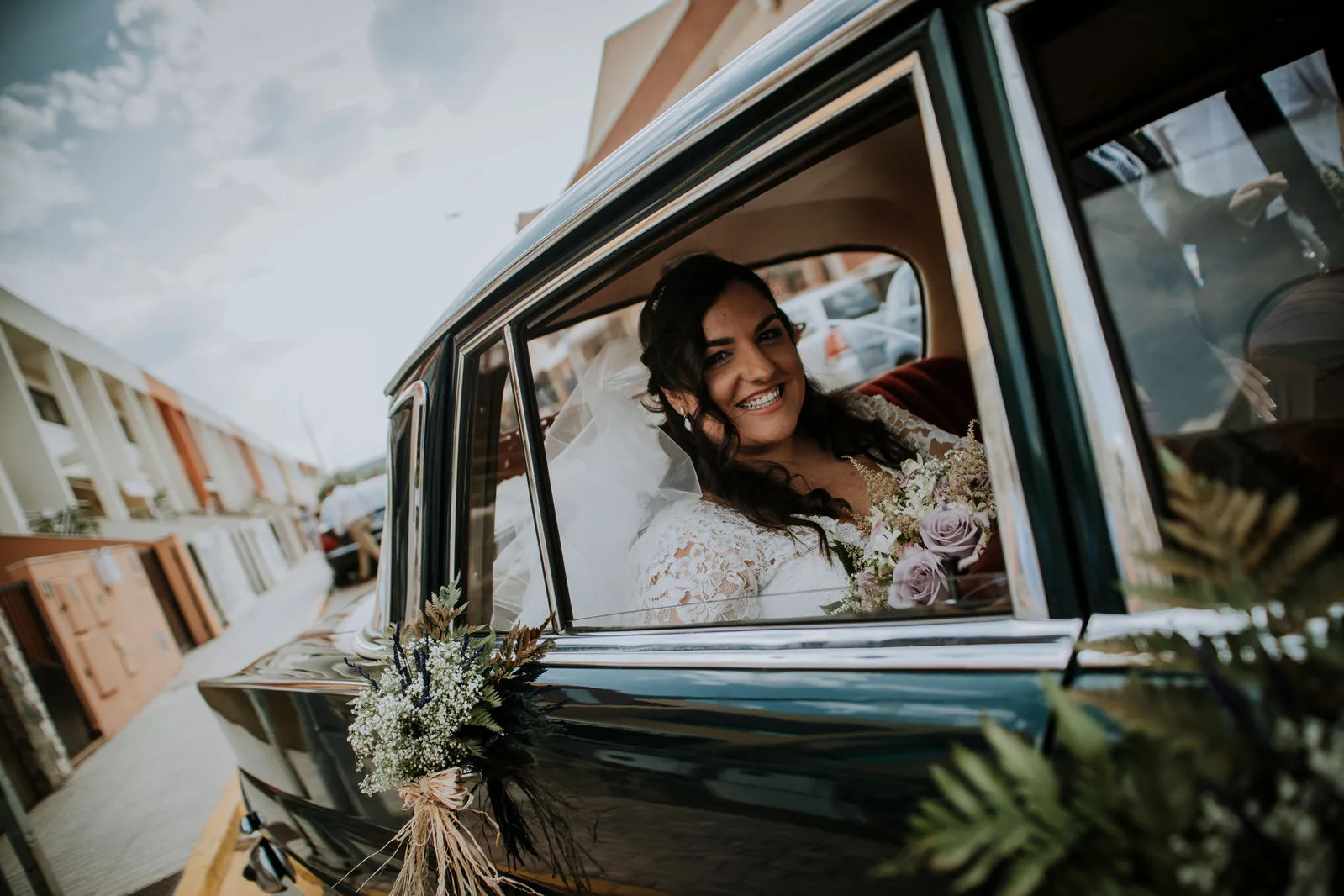Novia sonriendo desde un coche clásico