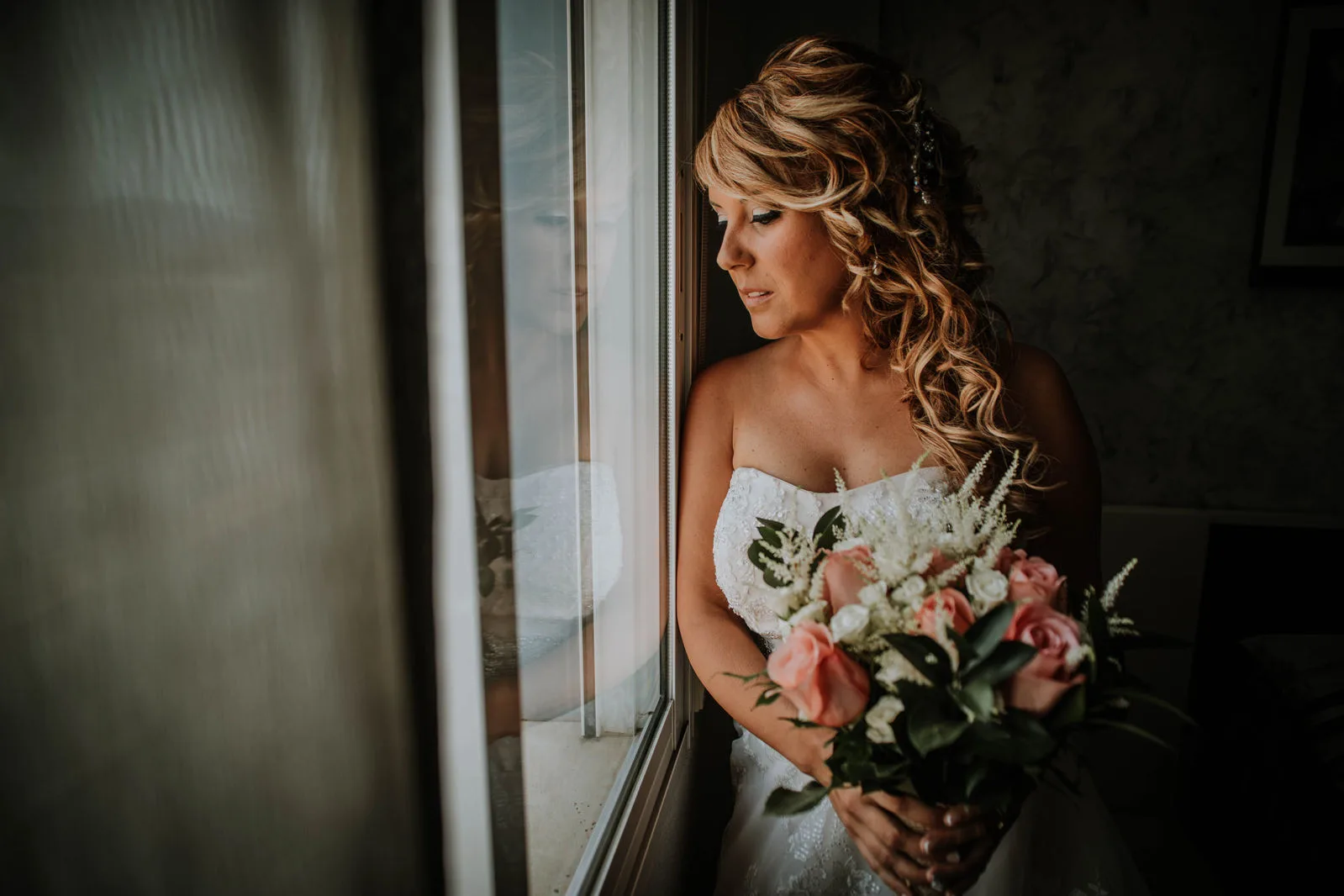 Retrato de una novia con su ramo junto a una ventana